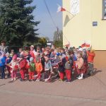 Dzieci przed budynkiem przedszkola z flagami w rękach