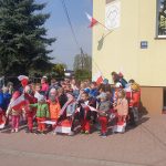 Grupa 1 - Dzieci przed budynkiem przedszkola z flagami Polski