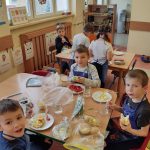 Grupa IV - Dzieci przy stoliku robią kanapki