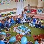 Grupa IV - Dzieci w kole na dywanie z niebieskimi balonami