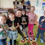 Grupa IV - Dzieci stoją trzymając w rękach zabawki dinozaury