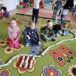 Grupa IV - Dzieci układają dinozaura na dywanie