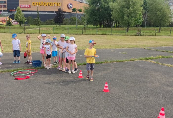 Grupa IV - Dzieci pokonują slalom z woreczkiem na głowie na boisku szkolnym