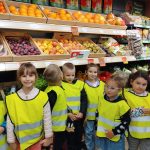 Grupa V -Dzieci stoją przy półkach z warzywami i owocami