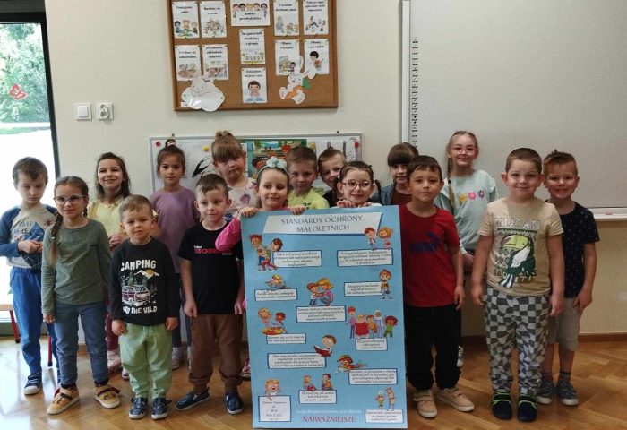 Grupa V - Dzieci stoją z plakatem Standardy Ochrony Małoletnich